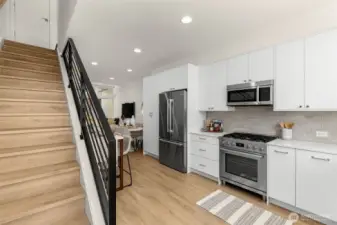 The kitchen and living areas connect with effortless flow, anchored by hardwood floors and designer lighting.