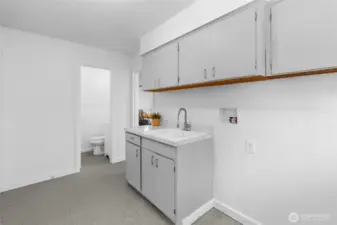 UTILITY BATHROOM | This tucked away bathroom features a toilet and sink. Located as you come into the home from the garage on the left. There is a door from the laundry room to the kitchen so you can close it for privacy.