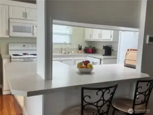 This kitchen features an eating bar, and to the left is the dining room. This entire area opens up to the living room with pellet stove, huge view windows showing the waterfront and the backyard with its beautiful waterfront seating.