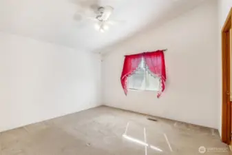 Primary bedroom with blinds, ceiling fan, and lovely curtains.  The bathroom is the door to the right.