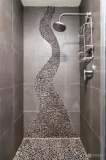 Stunning primary bathroom shower with custom stone inlay.