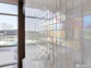 Ann Sacks Opalescent Mosaic Tumbled Tile meticulously installed one by one on the gas fireplace.