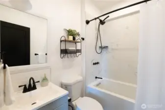 The main bathroom is adjacent to the living room and has also been fully updated with new tile, flooring, and fixtures