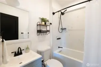 The main bathroom is adjacent to the living room and has also been fully updated with new tile, flooring, and fixtures
