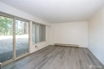 Living area with a large picture window and sliding glass door opening to the patio.