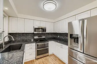 Updated kitchen with newer stainless appliances, granite counters, undermount lighting and extra deep sink.