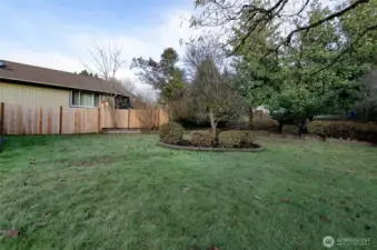 Large side yard has mature landscaping.  Partially fenced yard.