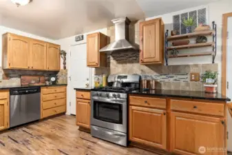 Enjoy cooking in this kitchen with gas stove, granite countertops and tile backsplash. Walk through the door into the garage and laundry area.