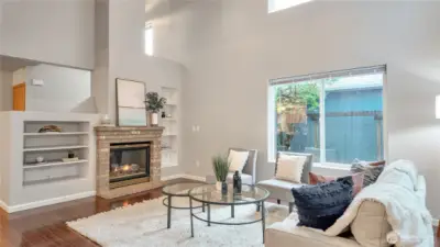 Vaulted Ceiling With Ceiling Fan. The Fireplace Completes The Warmth That The Built-In Book Shelves Add