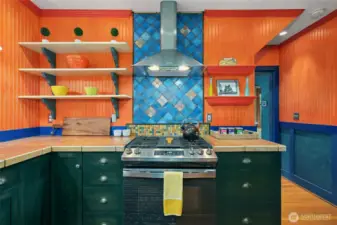 The wood paneled walls and deep green cabinets are common design elements found in the period.