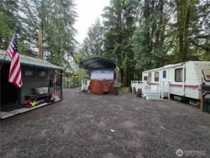 RVs both have porches and the outbuilding shown is a small shop.