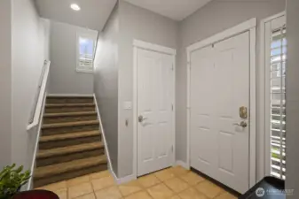 Staircase from tiled foyer with large closet under staircase.