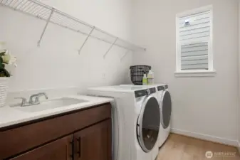 Laundry room includes washer, dryer, cabinet with sink