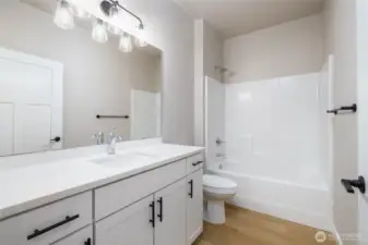The main bath has taller cabinets with quartz counters.