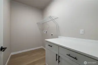 Laundry room has cabinet and folding counter.