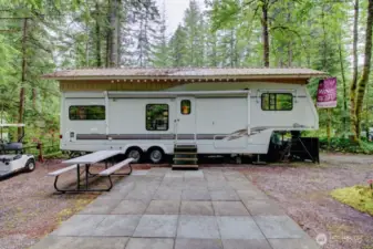 Overhang on trailer and concrete block patio is great to have at this property