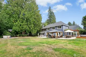 Grassy, sunny flat yard for summertime fun. Small sport court pictured to the left adjacent to trail access.