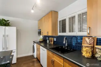 The kitchen features maple cabinets, new induction range, blue tile backsplash, Microwave, Bosch dishwasher, track lighting & W/D combo unit.
