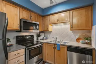 The kitchen is both functional and inviting, with warm wood cabinetry, stainless steel appliances, and a classic tile backsplash. Whether you're prepping a quick meal or entertaining a friend, this space delivers style and efficiency.