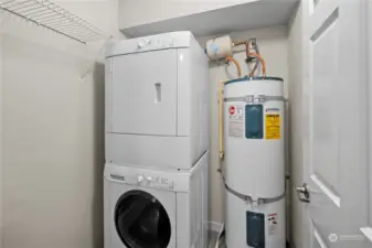 Utility room with stackable washer and dryer and electric hot water tank.