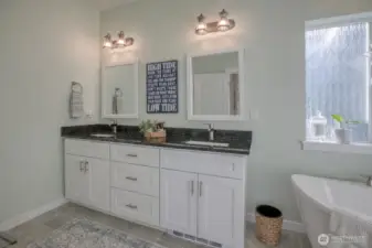 Double sink vanity with black granite counters, automatic under cabinet lighting, and toe kick heater