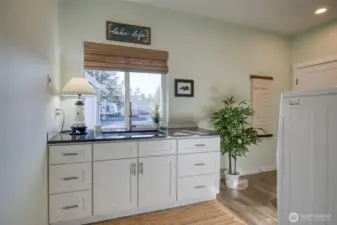 Large mudroom/laundry room with sink/dog washing station and side door access to the backyard