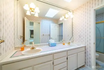 The main upstairs bath features a dual sink vanity with a ceramic tile counter and a wall-to-wall mirror.