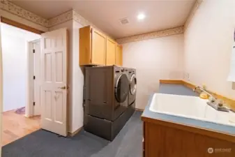A larger laundry/utility room with heavier-duty commercial-grade carpet, formica counter and a sink. Please note that the washer and dryer will not be remaining with the home.   Notice also the recessed lighting and the six-panel door.  The room has excellent cabinet space.