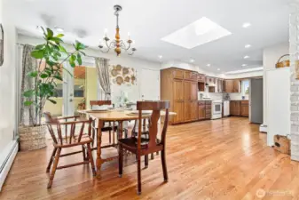 Expansive hardwood and large skylight in bright kitchen/dining area.