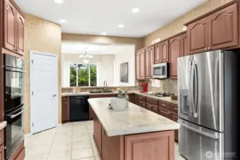 Open kitchen with pantry and island, tile counter tops and stainless and black appliances