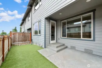 Fenced back patio and yard with low-maintenance turf.