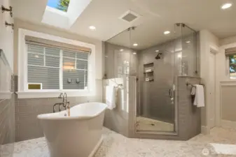 Beautifully updated primary bath showcasing marble mosaic floors, glass-enclosed shower, and soaking tub.