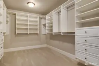 Expansive primary closet with built-in cabinetry and shelving.