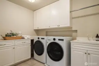 Expansive laundry room with utility sink, washer & dryer + built-ins.