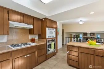 The large, central kitchen overlooks the lower family room.  Dressed in a custom cabinet design the trend of the times, the heart of the home offers space galore, plus a gas cooktop with overhead vent.  Make memories here.