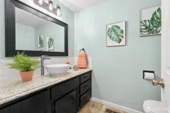 A pretty, upgraded half bath expresses the latest looks and color tones  Situated off passage between the entry and the kitchen dinning space, and at the top of the stairs to the lower level living areas.