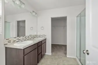 Primary bath with dual sink vanity, large shower, and a walk-in closet.