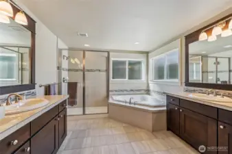 The primary bathroom is the perfect place to get ready for the day or to soak away the stress of a long day. Double vanities, step-in shower and large soaking tub are accented by beautiful tile works and rich wood cabinetry.