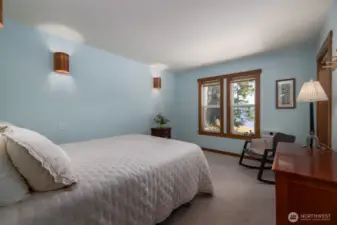 Primary bedroom on main floor has bay views out the large windows and lovely copper sconces.