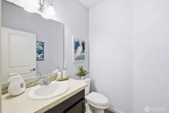 Main floor half-bath. It is tucked conveniently away from the commingling spaces, providing convenience and privacy, reducing bathroom stress at gatherings.