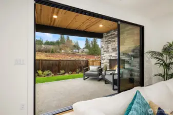 A stacking door system leads to a full luxury outdoor living space complete with covered patio and cozy outdoor gas fireplace