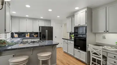 Granite countertops, newly painted cabinetry, under cabinet lighting, and an eating bar make this a bright and welcoming space.