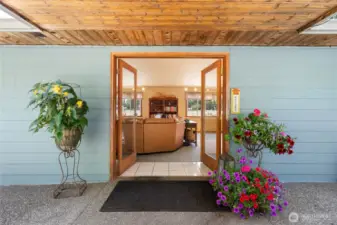 Welcoming front door with blooming flower pots and cedar accents.