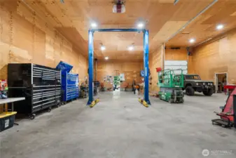 Fully functional workspace with custom shelving, high ceilings, and industrial lighting.