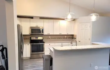 Bright Kitchen with Stainless Appliances, Quartz Counters, Tile Backsplash and Pantry