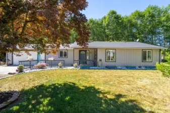 Charming country rambler with classic curb appeal, set on a peaceful lot framed by mature trees and open skies. This inviting front exterior features a covered entry, flower-lined walkway, and raised garden beds bursting with seasonal color. Enjoy the serenity of country living with a spacious front lawn, ideal for enjoying morning coffee, birdwatching, or quiet evenings under the stars. A tree-shaded driveway leads to the attached garage and welcoming front porch. If you're searching for a move-in ready home in a tranquil, rural setting with room to breathe—this is it.