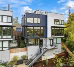 Blue home, one shared wall with white neighbor home. Perched high above the trees.