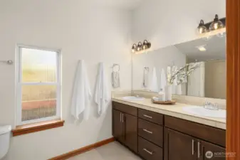 Primary ensuite features ceramic tile shower, a double sink vanity with fresh paint.