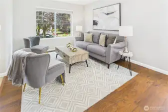 This beautifully staged living room boasts rich hardwood floors, large windows that flood the space with natural light. Thoughtfully designed with comfort and style in mind, it’s a space where you’ll love to relax or host.