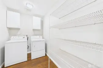 This well-designed laundry room is both practical and spacious, complete with washer, dryer, upper cabinetry, and extensive wire shelving for all your storage and organization needs.